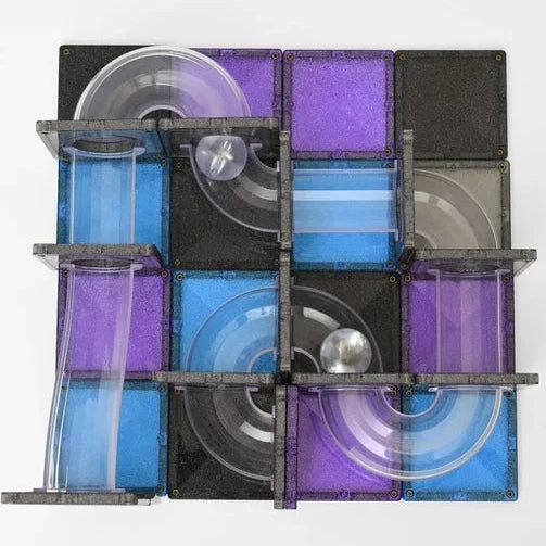 A square Connetix Galaxy magnetic tile toy with a maze-like track, featuring translucent blue and purple tiles, black tiles, clear plastic loops, and a small silver ball on a plain light gray background.