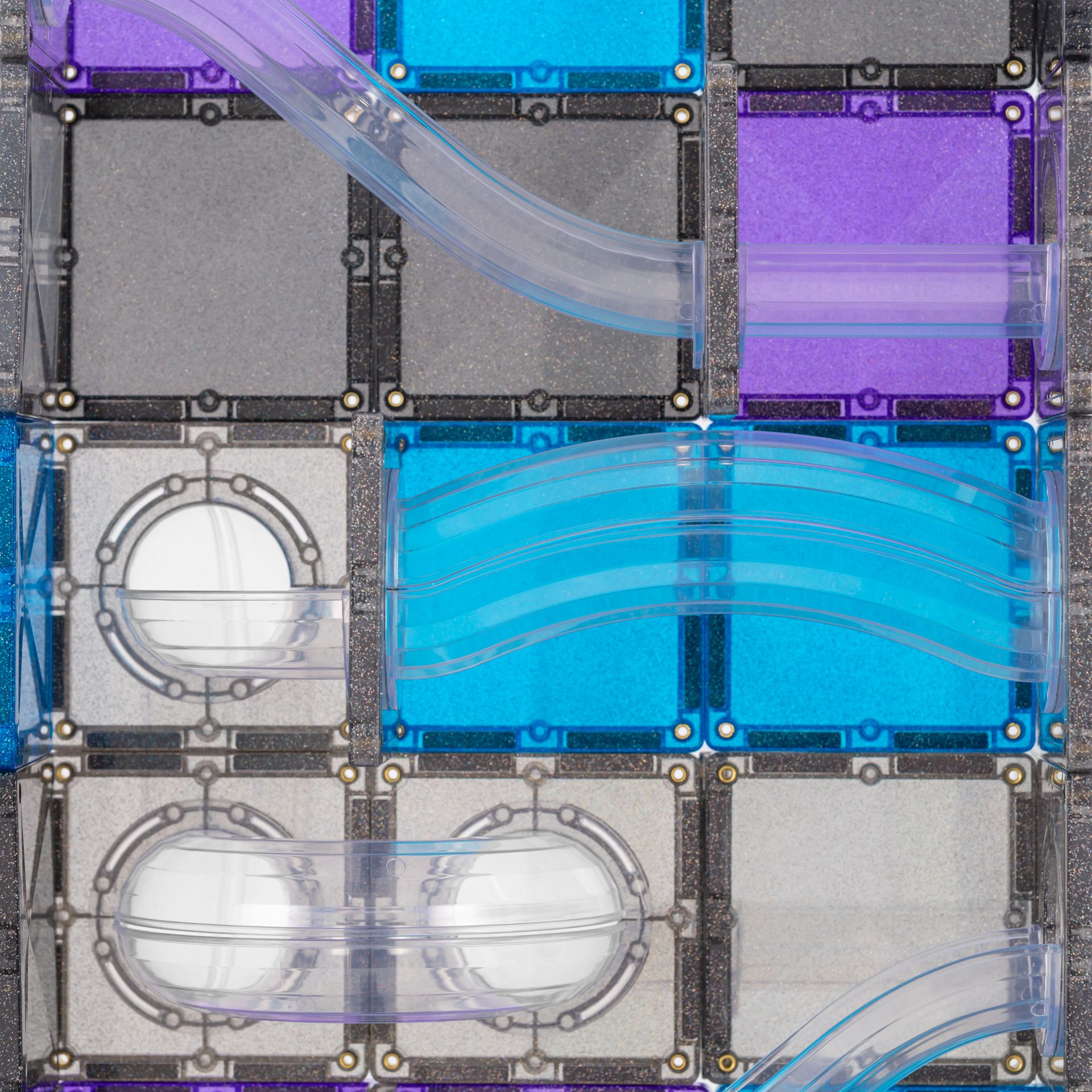 A close-up of a modular translucent acrylic or plastic tile wall system with square panels in gray, blue, purple, and white, connected by clear curved channels and framed by dark metal hardware Connetix Galaxy Pack Spotty Dot Toys. 